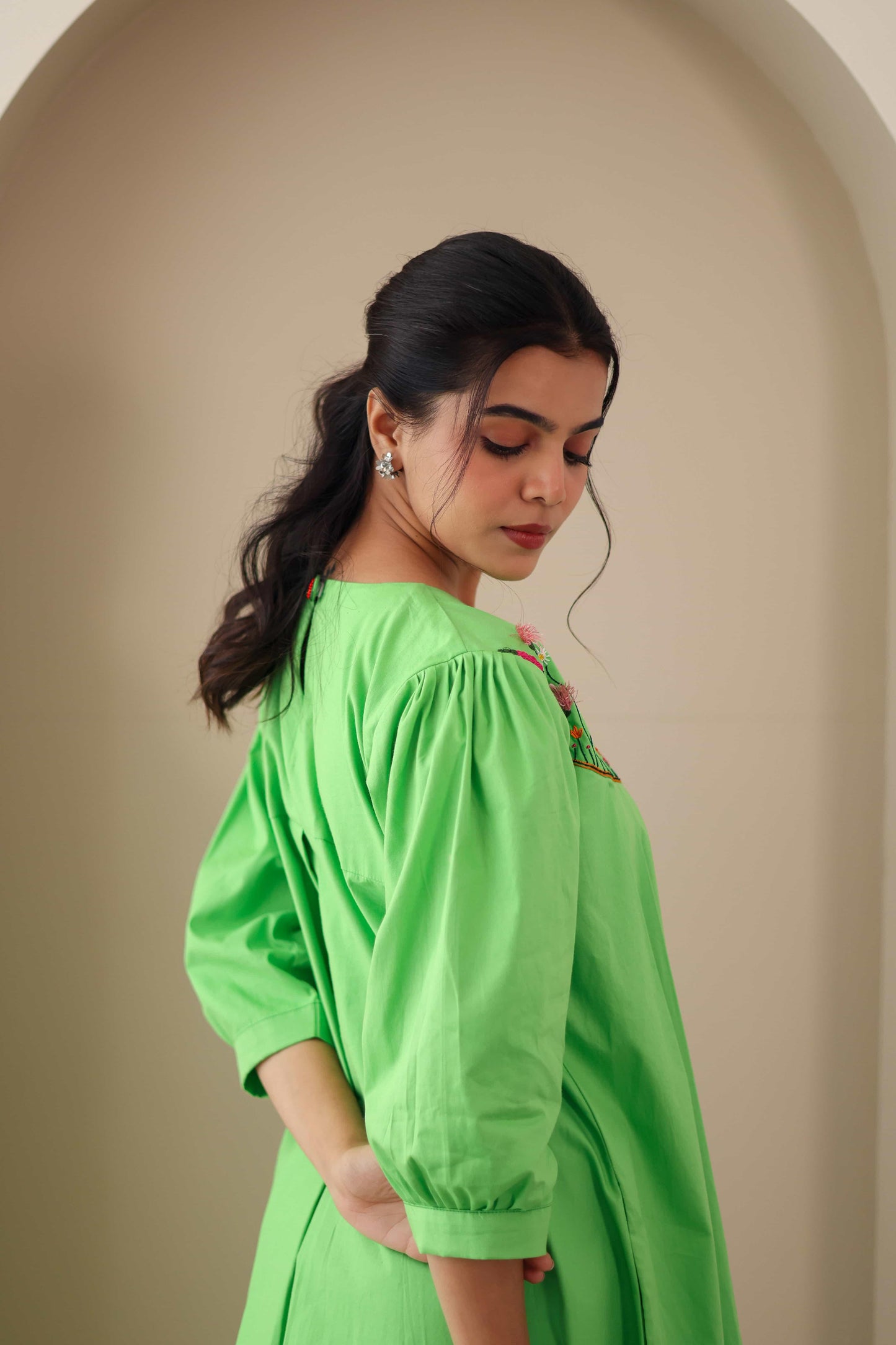 Woman in a green embroidered cotton poplin dress with puff sleeves, side view