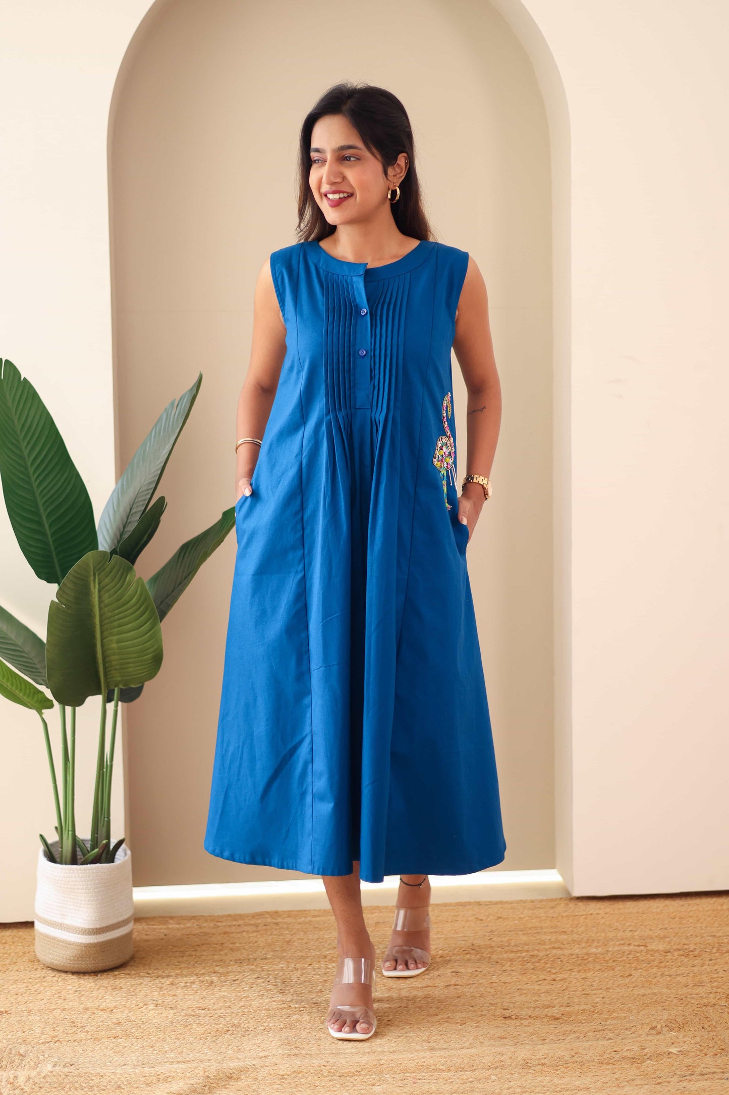 Woman wearing a sleeveless navy blue embroidered cotton dress with button front