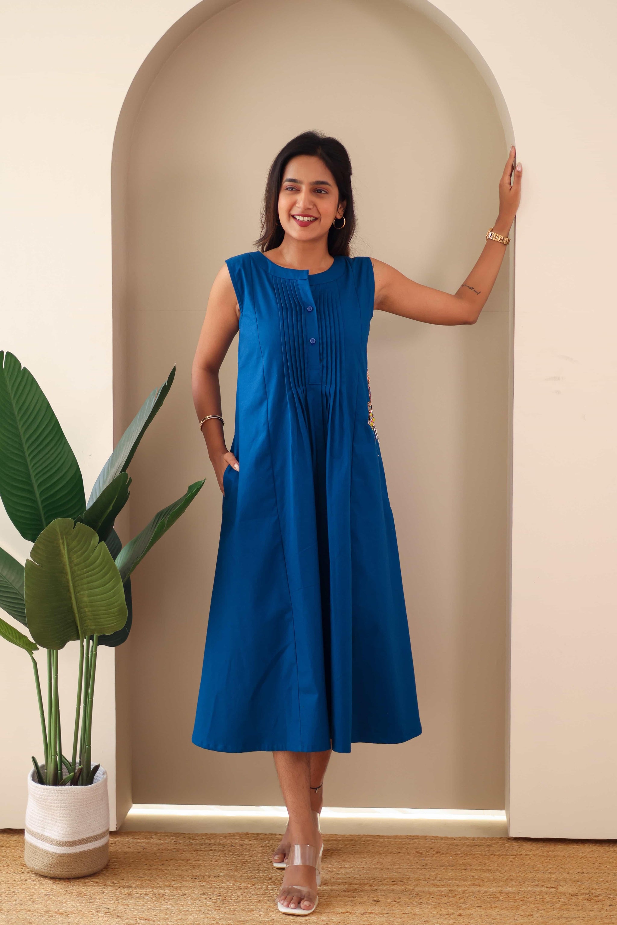 Woman wearing sleeveless navy blue embroidered cotton midi dress with pleated front