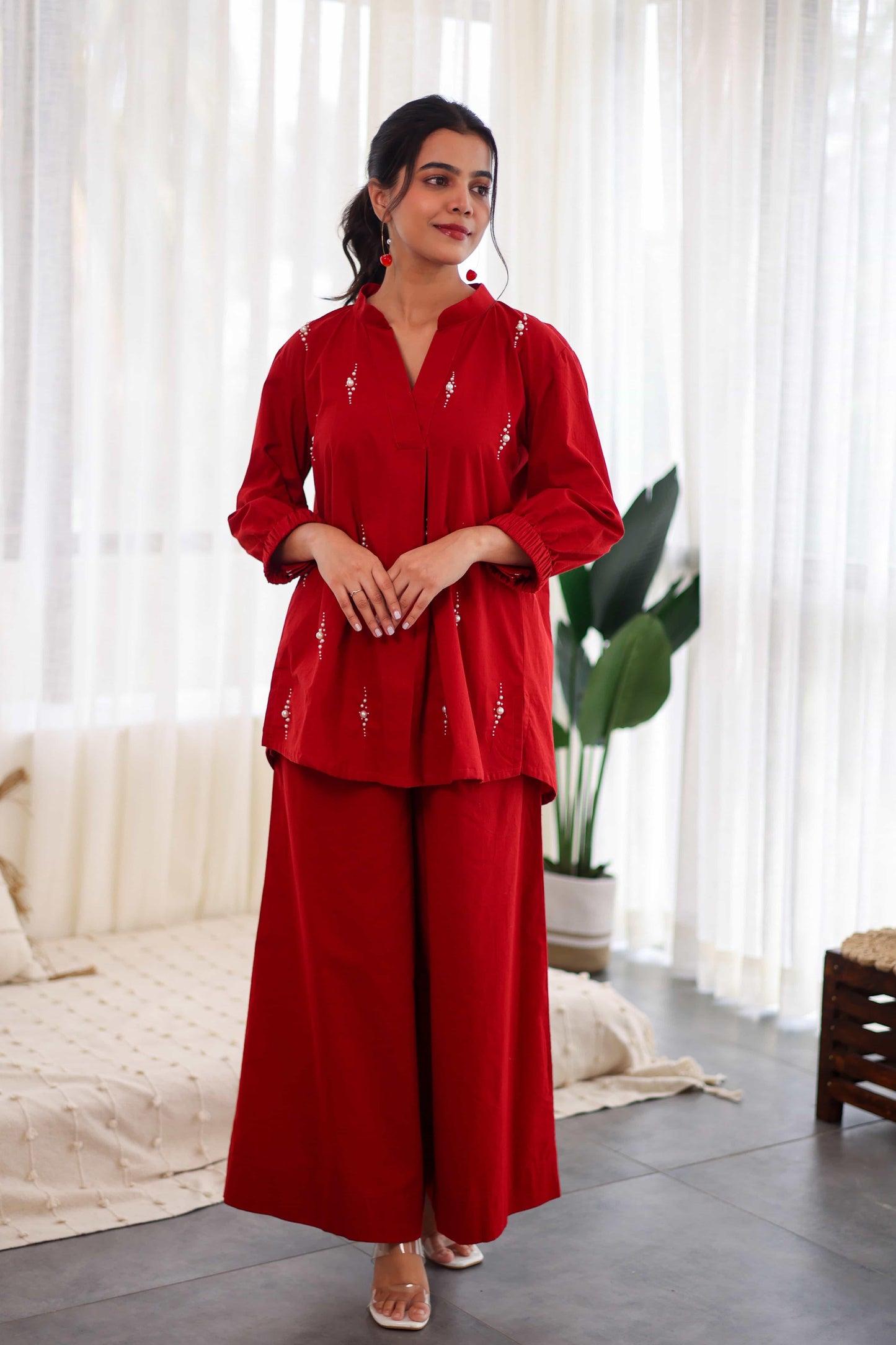 Woman in red embroidered cotton co-ord set with wide-leg pants and long top indoors