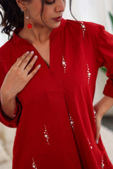 Woman wearing a red cotton co-ord set with pearl embroidery and a v-neckline