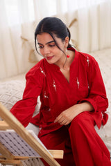 Woman in red pearl embroidered cotton co-ord set sitting indoors and painting