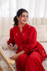 Woman in red embroidered cotton co-ord set relaxing indoors, holding a paintbrush